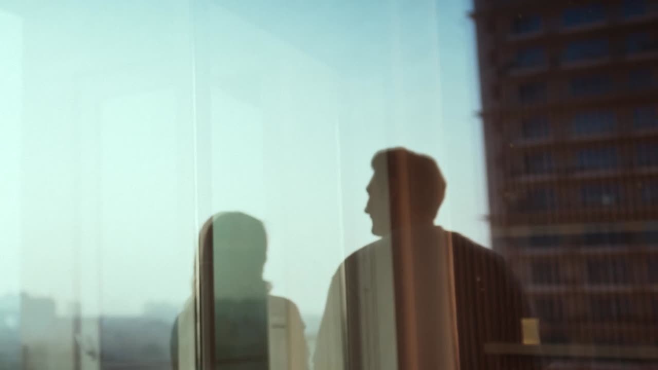 Film frame: two silhouettes in conversation by a window